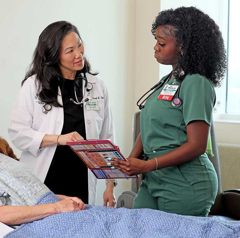 A female physician and a nurse reviewing a patient's chart.