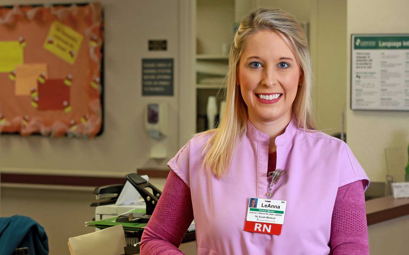 A smiling nurse wearing pink scrubs and a Lexington Health name tag.