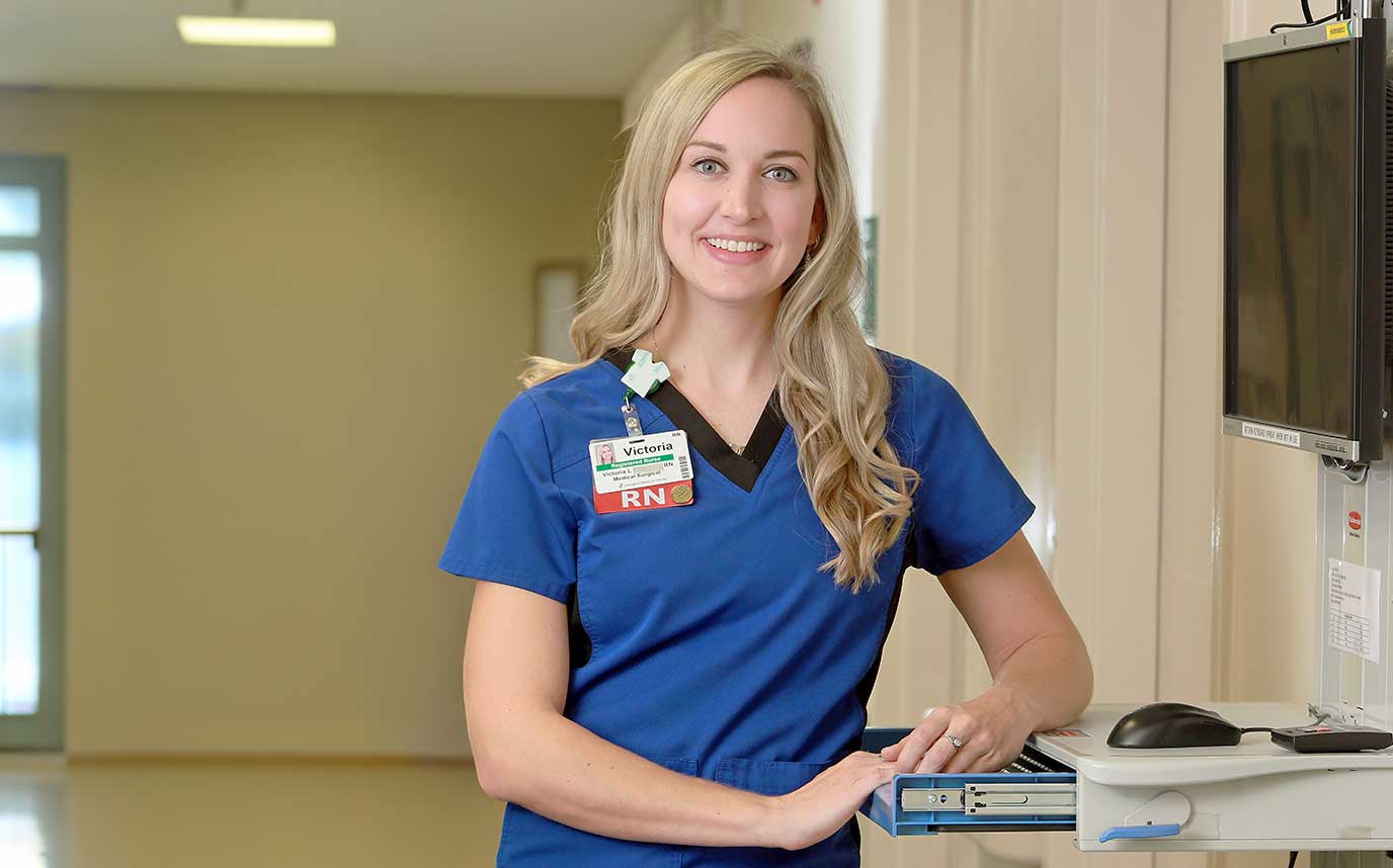 A smiling nurse wearing a blue smock and Lexington Health name tag.