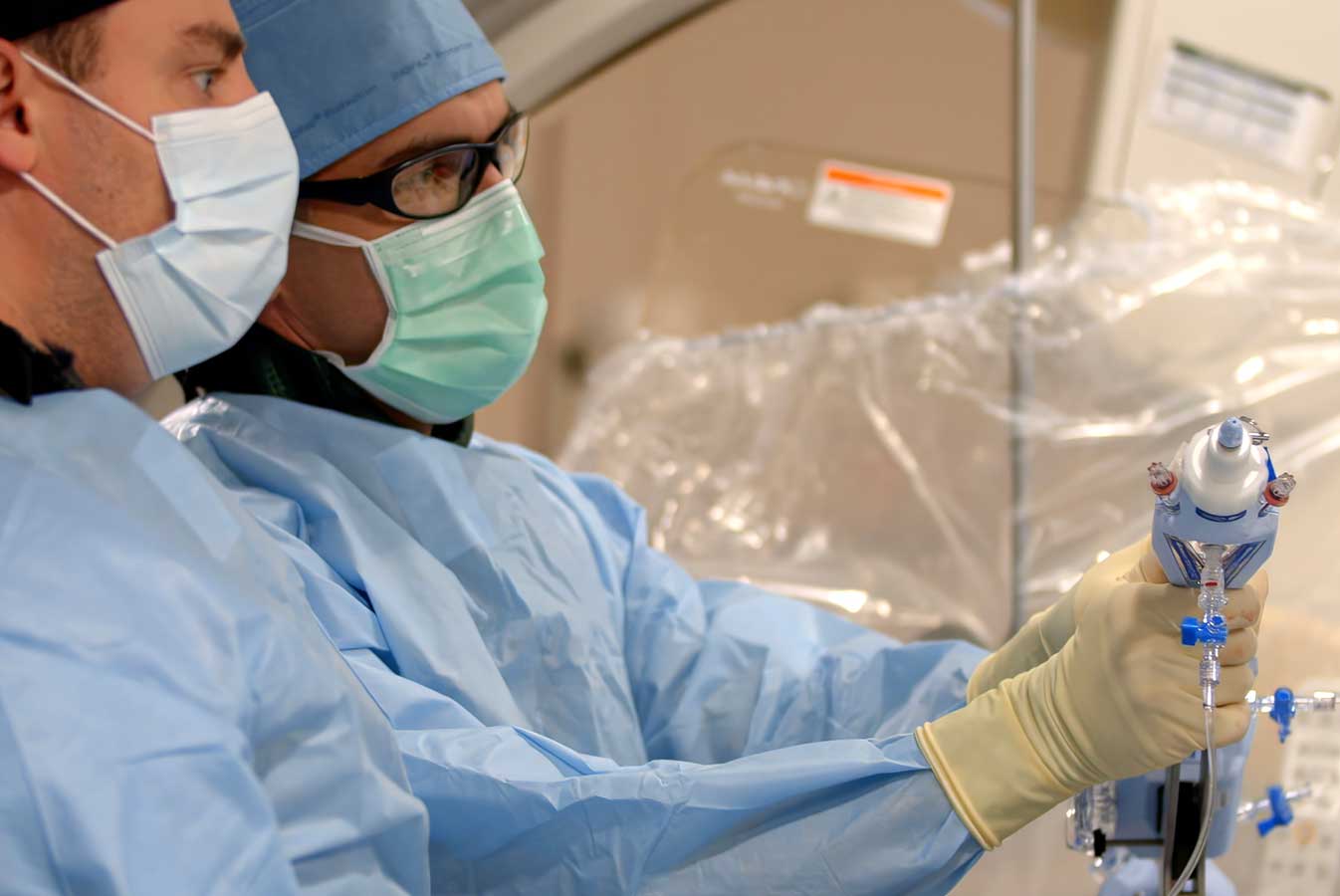 Surgeons wearing scrubs and using a medical device.