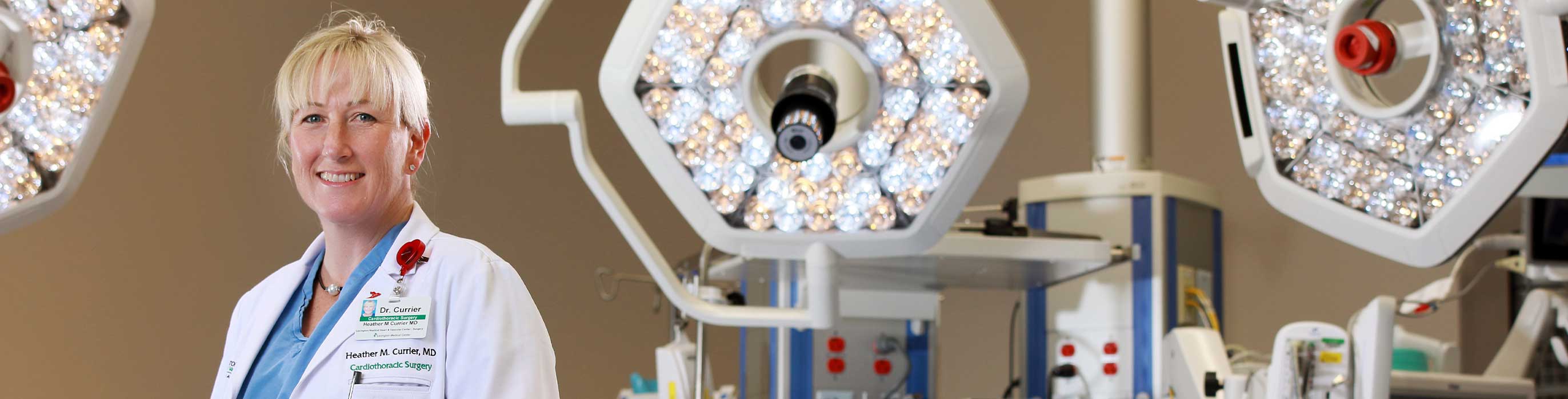 A female physician smiles in the operating room while wearing a white lab coat.