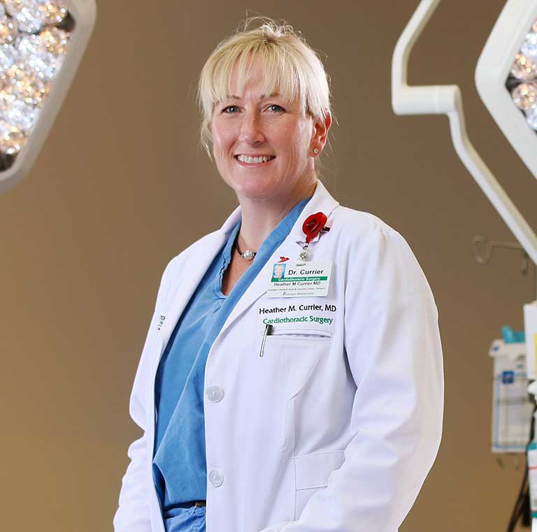 A smiling female physician wearing a white lab coat.